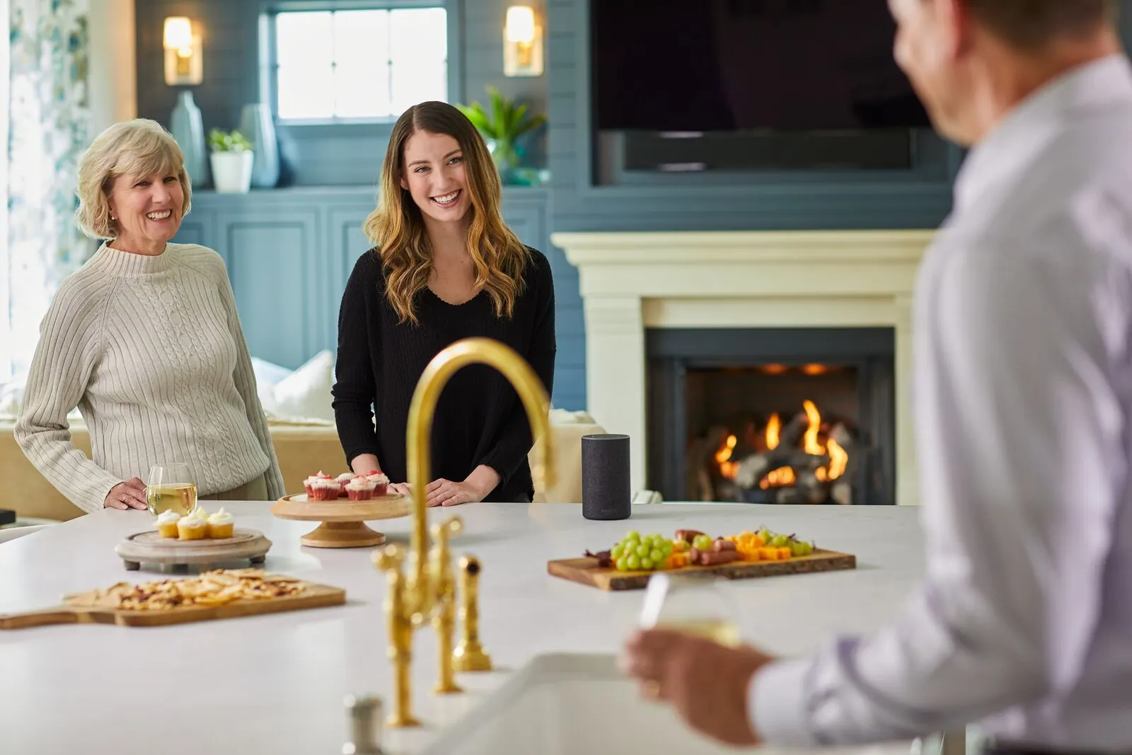 An evening gathering around an outdoor kitchen and a burning fire feature
